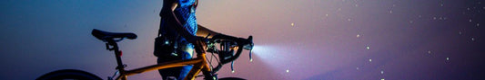 A bike light shining in the dark on a road bike.