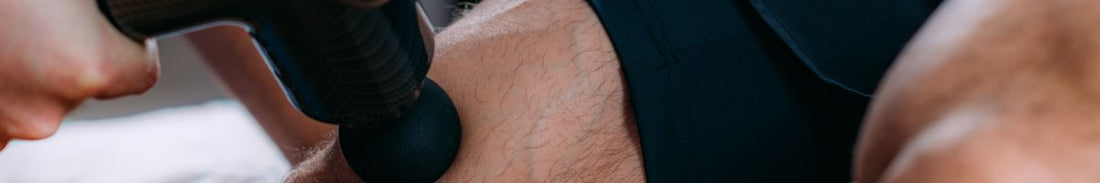 Using a massage gun on a man's thigh.