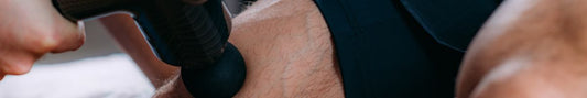 Using a massage gun on a man's thigh.