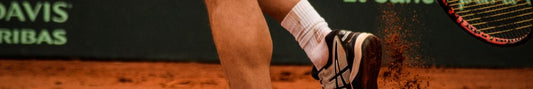 A man wearing tennis shoes holding a tennis racket.